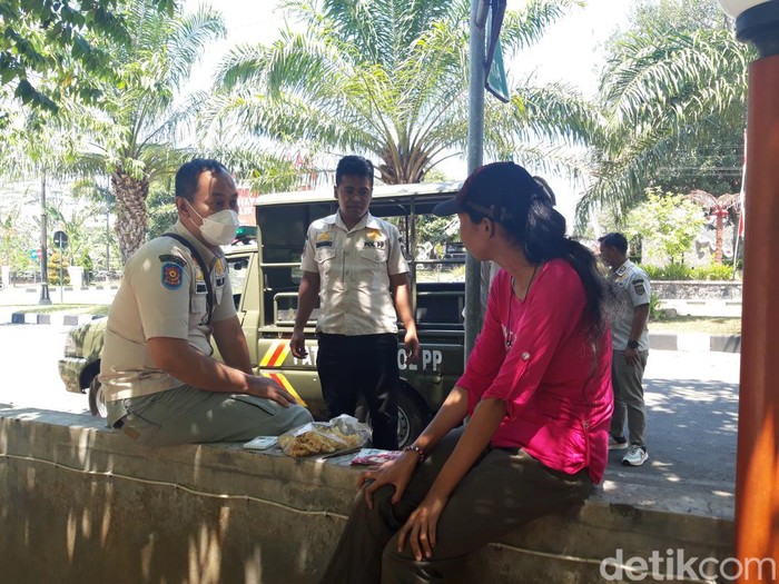 Anggota Satpol PP Boyolali saat membujuk wanita diduga depresi di pinggir jalan utara kantor DPRD Boyolali, Rabu (30/8/2023).