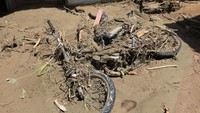 Sebuah motor tertimbun material lumpur banjir bandang. Puluhan warga juga terpaksa mengungsi akibat banjir bandang tersebut.