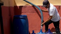 Petugas Palang Merah Indonesia (PMI) mengisi air ke dalam ember dan galon air milik warga di Desa Buata, Kabupaten Bone Bolango, Gorontalo. 