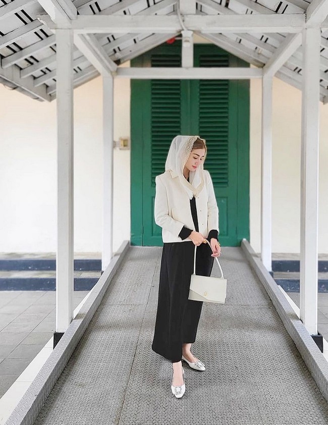 Gaya monokrom Novita membuatnya terlihat elegan dengan padanan blouse lengan panjang, celana kulot dan blazer serta kerudung putih. Foto: Instagram/@novitamochamad