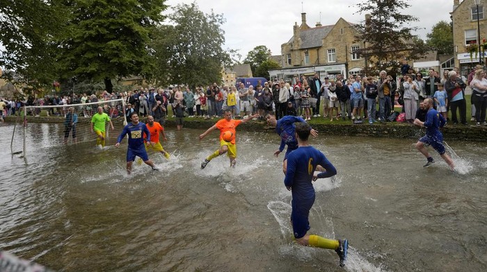 Tradisi Ratusan Tahun, Begini Serunya Main Bola di Sungai Windrush Inggris Footballers from Bourton Rovers fight for the ball during the annual traditional River Windrush football match, which has been taking place for over 100 years, in the Cotswolds village of Bourton-on-the-Water, England, Monday, Aug. 28, 2023. The event sees two teams of six from Bourton Rovers Football Club play a 30 minute football match in the usually calm river water. Goalposts are set up in the river and players attempt to score as many goals as possible, whilst getting all spectators as wet as possible in the process. (AP Photo/Frank Augstein)