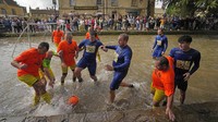 Pesepakbola Bourton Rovers berebut bola dalam pertandingan sepakbola tradisional tahunan River Windrush di desa Cotswolds, Bourton-on-the-Water, Inggris, Senin (28/8/2023).