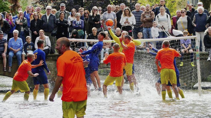 Footballers from Bourton Rovers fight for the ball during the annual traditional River Windrush football match, which has been taking place for over 100 years, in the Cotswolds village of Bourton-on-the-Water, England, Monday, Aug. 28, 2023. The event sees two teams of six from Bourton Rovers Football Club play a 30 minute football match in the usually calm river water. Goalposts are set up in the river and players attempt to score as many goals as possible, whilst getting all spectators as wet as possible in the process. (Ben Birchall/PA via AP)