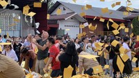 Para peserta merayakan Festival Hantu Lapar dengan menghamburkan kertas kuning yang berisi doa-doa ke langit.
