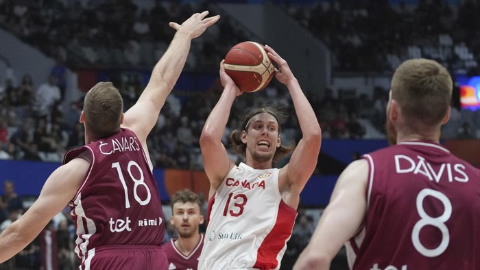 Canada forward Kelly Olynyk (13) drives against Latvia center Klavs Cavars (18) and forward Davis Bertans (8) during the Basketball World Cup group H match between Canada and Latvia at the Indonesia Arena stadium in Jakarta, Indonesia, Tuesday, Aug. 29, 2023. (AP Photo/Tatan Syuflana)