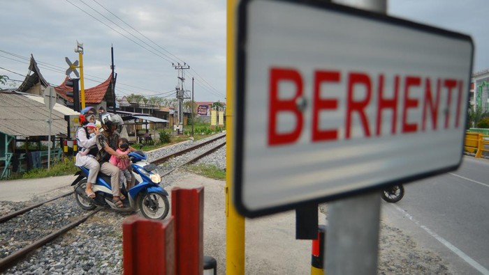 Pengendara motor menunggu kereta api lewat di perlintasan sebidang di Padang, Sumatera Barat, Rabu (30/8/2023). PT KAI Divre II Sumbar tahun ini menutup lima perlintasan sebidang yang liar di Padang dari total 112 perlintasan sebidang untuk meningkatkan keselamatan perjalanan kereta api. ANTARA FOTO/Iggoy el Fitra/nym.