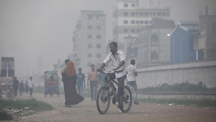 People sit on a rail track as smoke rises from steel mills near a slum in Dhaka, Bangladesh August 29, 2023. REUTERS/Mohammad Ponir Hossain