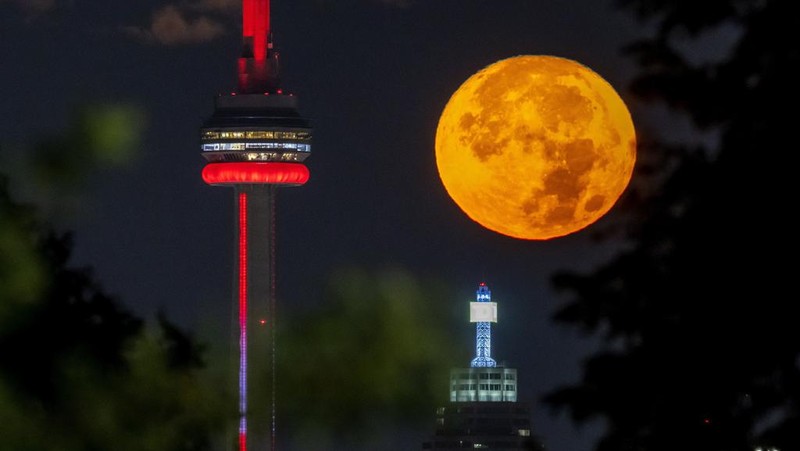 The August Super Blue Moon sets behind the CN tower in Toronto on Wednesday August 30, 2023.  The cosmic curtain rises Wednesday night with the second full moon of the month, the reason it’s considered blue. It’s dubbed a supermoon because it’s closer to Earth than usual, appearing especially big and bright. (Frank Gunn /The Canadian Press via AP)