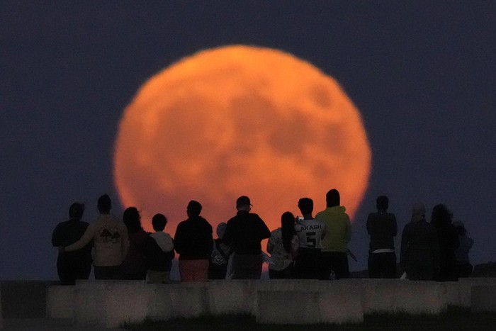 A rare Blue Supermoon rises over Lake Michigan as spectators watch from Chicagos 31st Street beach Wednesday, Aug. 30, 2023. (AP Photo/Charles Rex Arbogast)