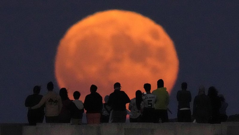 A rare Blue Supermoon rises over Lake Michigan as spectators watch from Chicago's 31st Street beach Wednesday, Aug. 30, 2023. (AP Photo/Charles Rex Arbogast)