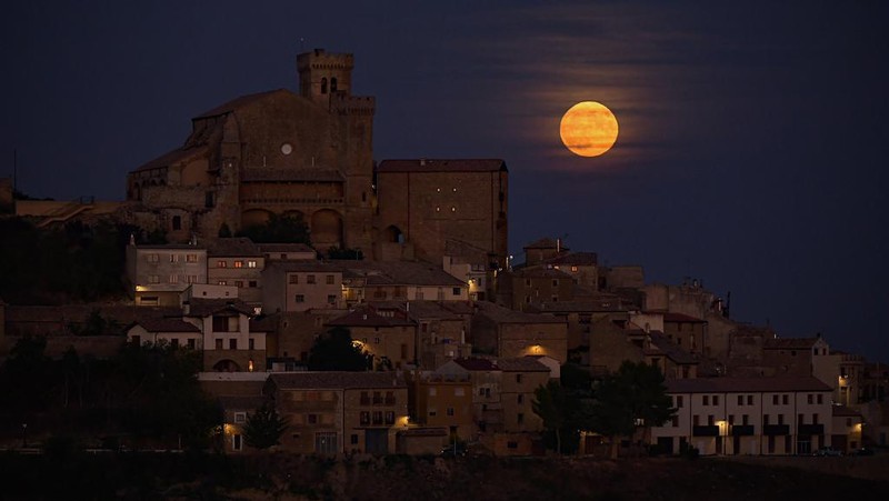 The moon known as blue moon rises behind the small village of Ujue, northern Spain, Wednesday, Aug. 30, 2023. (AP Photo/Alvaro Barrientos)