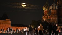 The August Super Blue Moon sets behind a historical building and the St. Basils Cathedral, right, as people walk in Red Square in Moscow, Russia, Wednesday, Aug. 30, 2023. The cosmic curtain rises Wednesday night with the second full moon of the month, the reason it is considered blue. It is dubbed a supermoon because it is closer to Earth than usual, appearing especially big and bright. (AP Photo/Alexander Zemlianichenko)