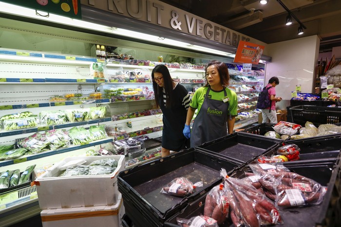 A shopper looks at  near empty shelves at a supermarket as super typhoon Saola approaches Hong Kong on Friday, Sept. 1, 2023. Most of Hong Kong and parts of southern China ground to a near standstill as Super Typhoon Saola edged closer Friday. (AP Photo/Daniel Ceng)