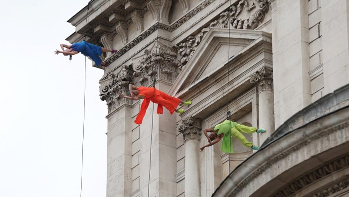 Members of the public watch dancers from vertical dance company BANDALOOP perform while suspended from St Paul's Cathedral, on the opening evening of the City of London's reimagined Bartholomew Fair, in London, Britain, August 31, 2023. REUTERS/Hollie Adams