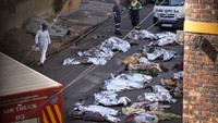 Petugas medis berdiri di samping jenazah para korban kebakaran di pusat kota Johannesburg, Kamis (31/8/2023). (AP Photo/Jerome Delay)
