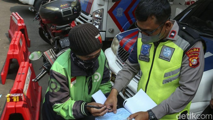 Seorang pengemudi ojek online ditilang polisi usai dinyatakan tidak lulus uji emisi di Dirlantas Polda Metro Jaya, Jakarta, Jumat (1/9/2023).
