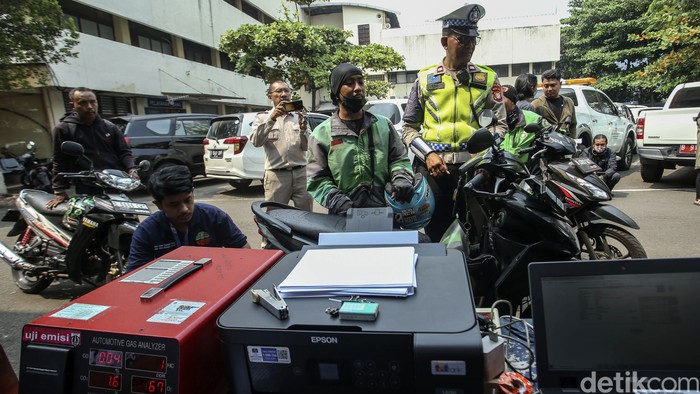 Seorang pengemudi ojek online ditilang polisi usai dinyatakan tidak lulus uji emisi di Dirlantas Polda Metro Jaya, Jakarta, Jumat (1/9/2023).