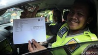 Polisi menunjukkan surat bahwa kendaraannya telah lulus uji emisi.  