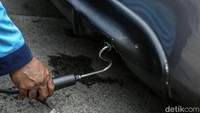 Petugas uji emisi melakukan pengujian asap kendaraan bermotor.  