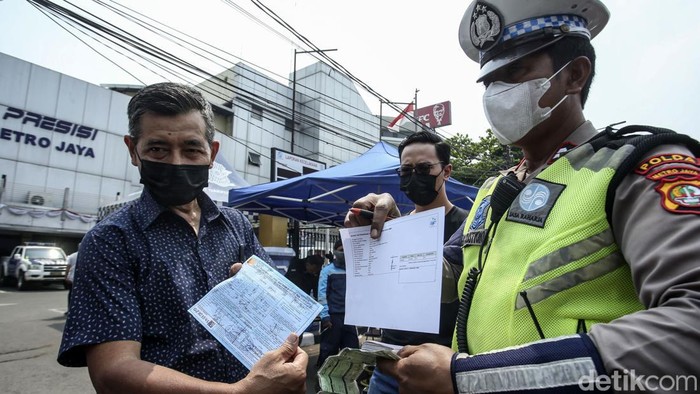 Polisi menilang pengendara mobil yang tidak lolos uji emisi di Depan Dirlantas Polda Metro Jaya, Jakarta, Jumat (1/9/2023). Polda Metro Jaya hari ini mulai menggelar razia kendaraan bermotor untuk mengikuti uji emisi. Kendaraan yang tak mengikuti atau tak lulus uji emisi akan dikenakan sanksi tilang yang akan menyesuaikan standar prosedur yang berlaku.