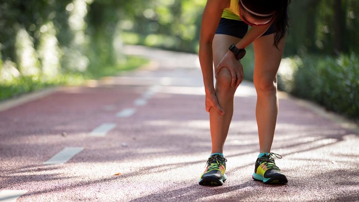 Female runner suffering with pain on sports running knee injury