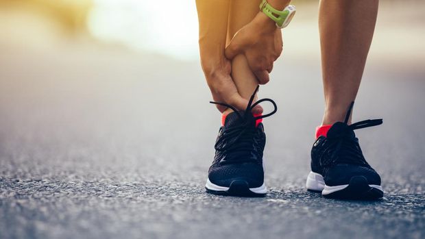 woman runner hold her injured leg on road