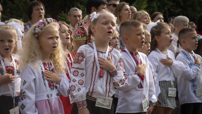 Anak-anak Ukraina menyanyikan lagu kebangsaan saat masuk hari pertama sekolah di Bucha untuk tahun ajaran baru. (AP Photo/Efrem Lukatsky)