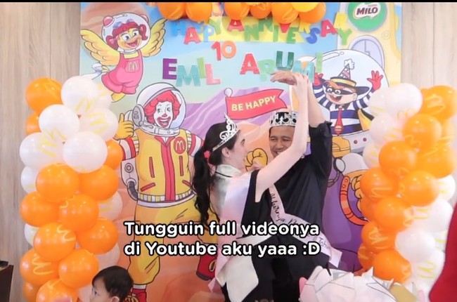 Arumi Bachsin dan Emil Dardak mendapatkan perayaan pesta ulang tahun pernikahan di McDonald’s. Dekorasinya dihiasi dengan balon oranye-putih yang ramai seperti ulang tahun anak. Foto: Dok. Instagram