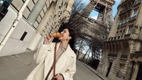 Jessica Mila terlihat cantik dan stylish saat jalan-jalan di Paris. Ia tampak menikmati croissant jumbo di tangannya. Foto: Instagram @jscmila