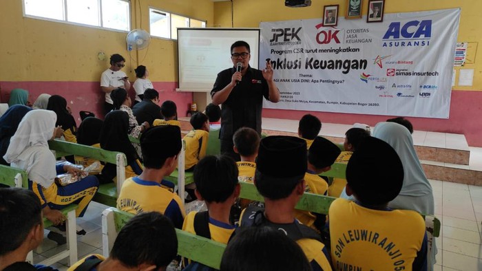 Momen Anak-anak Sekolah Belajar Literasi Keuangan Analis Senior Deputi Direktur Pelaksanaan Edukasi Keuangan OJK Arinengwang Gusta Galung Raharjo (kedua kanan) bersama Kepala Sekolah SDN Leuwiranji Supriyati (kanan) Kepala Divisi Media dan Marketing Communication PT Asuransi Central Asia (ACA), Sugiarto (kedua kiri) dan MarCom Dept Head PT Asuransi Bintang Tbk Putu Saputro, menyapa siswa sekolah dasar selepas menyerahkan bantuan perlengkapan sekolah, di SDN Leuwiranji 05 Rumpin, Bogor, Jawa Barat , Sabtu (2/9/2023).