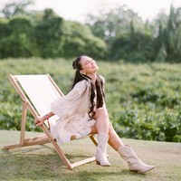 Luna Maya mengenakan mini dress warna ivory dengan detail lace dan pom pom. Dia memadukan busana dengan boots warna senada. Foto: Instagram/@lunamaya