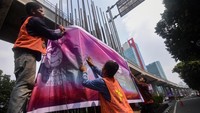 Petugas memasang banner KTT ASEAN di tiang monorel di Jalan Rasuna Said, Jakarta, Minggu (3/9/2023).  