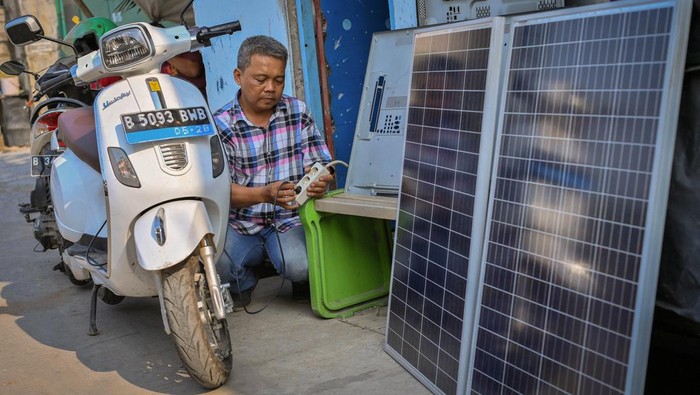 Mandiri Menuai Matahari Nur Rohmandi memanfaatkan listrik hasil produksi dari PLTS yang terpasang di bengkel elektronik miliknya untuk mengisi baterai sepeda motor listrik di Kapuk, Jakarta Barat, DKI Jakarta.