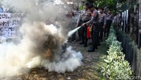Polisi yang berjaga memadamkan api yang membakar ban bekas.  
