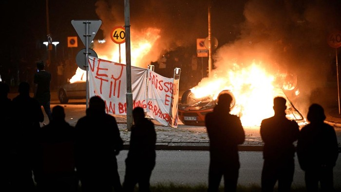 People are silhouetted as cars burn during a riot in Malmo, Sweden September 4, 2023.  TT News Agency/Johan Nilsson via REUTERS      ATTENTION EDITORS - THIS IMAGE WAS PROVIDED BY A THIRD PARTY. SWEDEN OUT. NO COMMERCIAL OR EDITORIAL SALES IN SWEDEN.