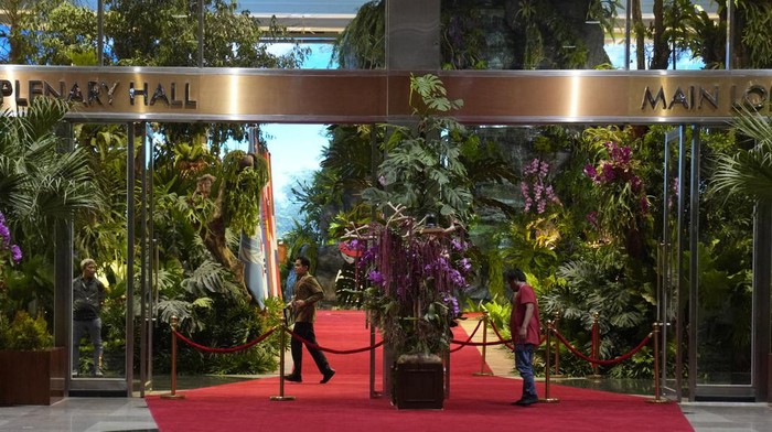 Penampakan Hutan Selamat Datang KTT ASEAN di JCC Senayan Members of the delegates walk among trees used to decorate the Jakarta Convention Center, the venue of the Association of Southeast Asian Nations (ASEAN) Summit in Jakarta, Indonesia, Tuesday, Sept. 5, 2023. Indonesian President Joko Widodo will welcome fellow Asian and world leaders with a captivating jungle scene of a two-story waterfall, wild orchids and even an orangutan perched up a tree. (AP Photo/Dita Alangkara, Pool)