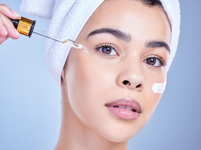 Ilustrasi wanita memakai serum wajah alternatif pengganti retinol.