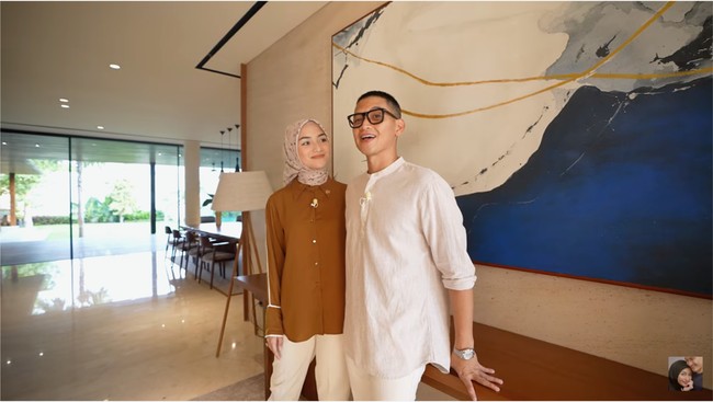 Sebuah lukisan bergaya abstrak langsung menyambut di area dalam bagian depan. “Ini warnanya beda dari warna kayu-kayu yang lain supaya biar kontras saja,” kata Rezky di video house tour rumah mereka yang tayang di YouTube, Sabtu (2/9/2023). (Foto: YouTube/CikyCitraRezky)