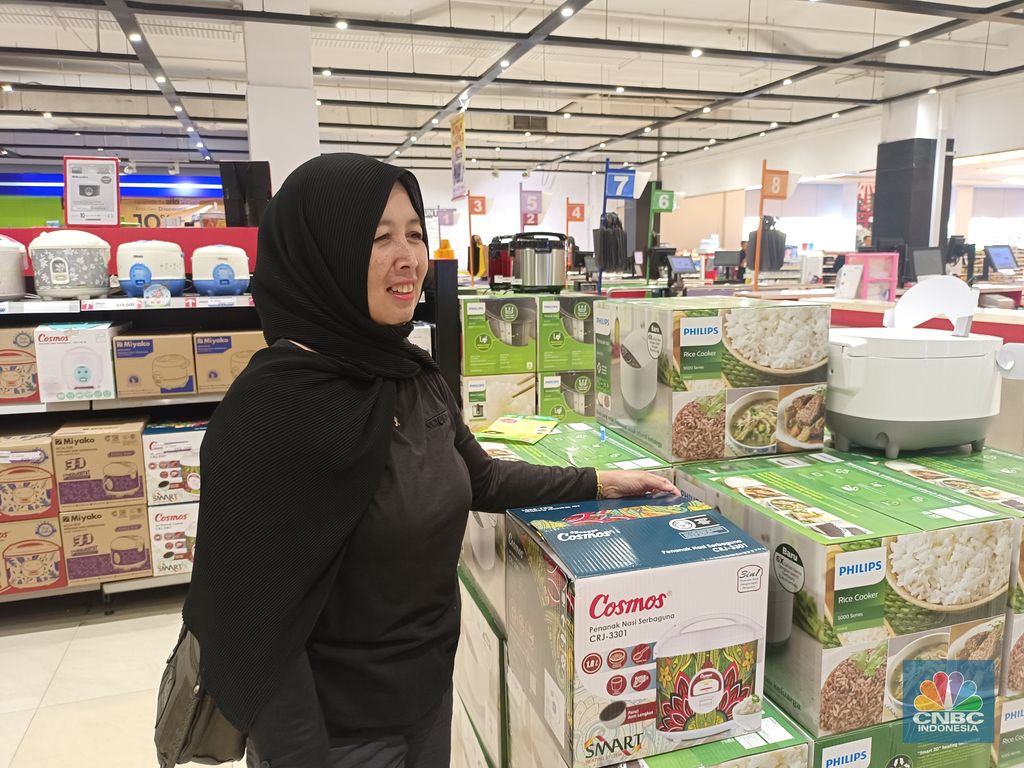 Seorang pengunjung Transmart Cempaka Putih Jakarta Pusat tertarik memboyong alat dapur elektronik, penanak nasi yang dibanderol dengan harga Rp 320.000 selama promo besar-besaran di Transmart bertajuk September Ceria di Transmart Full Day Sale. (CNBC Indonesia/Martyasari Rizky)