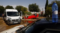 Warga mencoba mendorong kendaraan keluar dari lumpur dengan latar belakang terlihat mobil terbalik, menyusul hujan lebat, di El Alamo, Spanyol 4 September 2023.  
