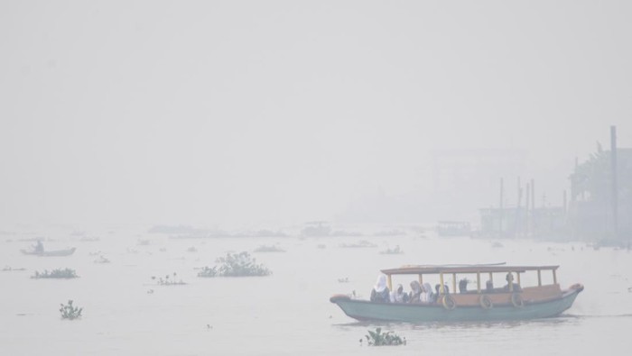 Sejumlah pelajar berangkat sekolah menggunakan perahu tradisional melewati kawasan yang diselimuti kabut asap di Sungai Ogan, Palembang, Sumatera Selatan, Rabu (6/9/2023). Kabut asap tersebut merupakan dampak dari kebakaran hutan dan lahan yang terjadi diberbagai Kabupaten yang ada di Provinsi Sumatera Selatan. ANTARA FOTO/Nova Wahyudi/tom.