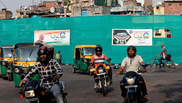 A boy pulls up plastic sheeting placed to screen a slum area alongside a road ahead of the G20 Summit in New Delhi, India, September 7, 2023. REUTERS/Amit Dave