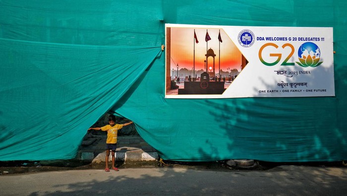 A boy pulls up plastic sheeting placed to screen a slum area alongside a road ahead of the G20 Summit in New Delhi, India, September 7, 2023. REUTERS/Amit Dave