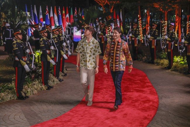 Pilihan bawahan juga kontras. Xavier, yang saat ini berusia 15 tahun, mengandalkan celana khaki yang memberikan kesan kasual. Adapun PM Trudeau tampil lebih formal dengan celana hitam. (Foto: Mast Irham/Pool Photo via AP)