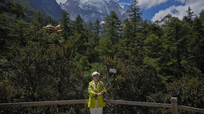 Menjelajahi Cagar Alam Yading di China yang Menyegarkan Mata A Chinese couple wearing Tibetan costumes pose for a souvenir photo against the Chonggu Monastery and snow-capped mountain as they visit the Yading nature reserve in Daocheng county, Ganzi Tibetan Autonomous Prefecture of southwestern China's Sichuan province, Wednesday, Sept. 6, 2023. (AP Photo/Andy Wong)