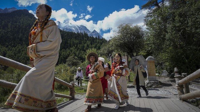 Menjelajahi Cagar Alam Yading di China yang Menyegarkan Mata A Chinese couple wearing Tibetan costumes pose for a souvenir photo against the Chonggu Monastery and snow-capped mountain as they visit the Yading nature reserve in Daocheng county, Ganzi Tibetan Autonomous Prefecture of southwestern China's Sichuan province, Wednesday, Sept. 6, 2023. (AP Photo/Andy Wong)