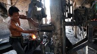 Pandai besi membuat sabit menggunakan mesin tempa modern di Desa Puncangsimo, Kecamatan Bandarkedungmulyo, Kabupaten Jombang, Jawa Timur, Kamis (7/9/2023).  