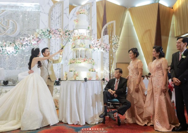 Ada momen di mana Desy Genoveva eks JKT48 dan Kelvin Prasetya memotong kue pernikahan tujuh tingkat berhiaskan lampu dan mawar. Foto: Instagram @desygenoveva_/dok. Wedding Factory