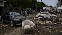 Orang-orang berjalan di samping kendaraan dan perabotan yang berserakan pasca banjir. Banjir yang melanda Istanbul berdampak pada lebih dari 1.750 rumah dan tempat usaha di kota tersebut, menurut kantor gubernur Istanbul. AP/Khalil Hamra