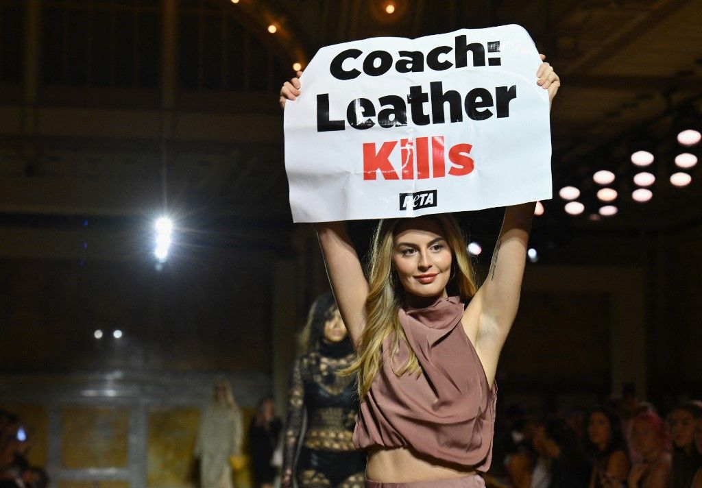 Aksi Protes di Fashion Show Coach A Peta protestor holds a sign reading
